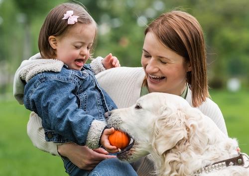 A mother and her special needs child playing with a dog
